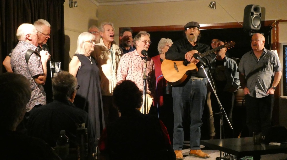 Group of musicians singing on stage at he Dunedin Folk Club in Otago, New Zealand.